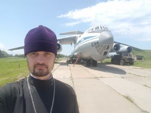Священник Сергий Качев у борта самолета